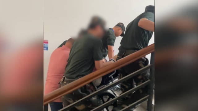 高考考生坐轮椅赴考，学校校警暖心守护将其抬上楼