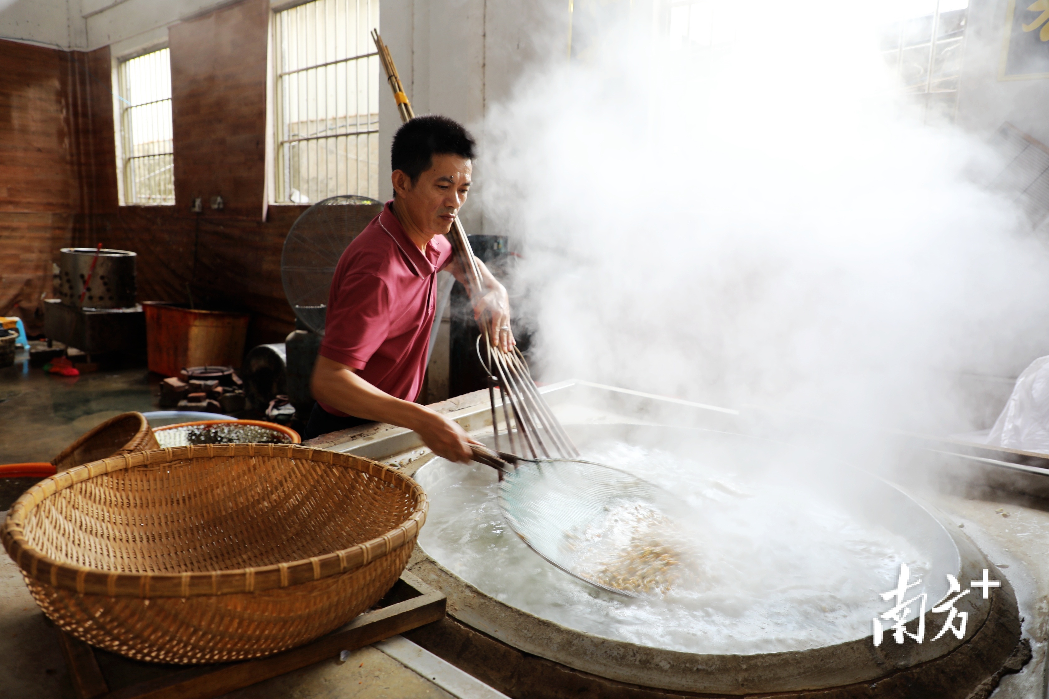 林群壮熟练地挥舞着竹扒，搅动着大鼎里煮沸的薄壳，使其壳肉分离。