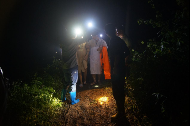 工作人员走山路护送孕妇前往广连高速水边入口