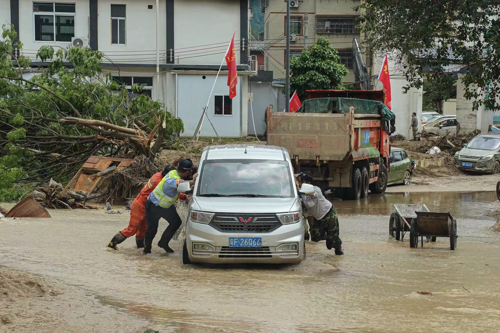 江湾镇，人们帮助一辆面包车通过水浸区。