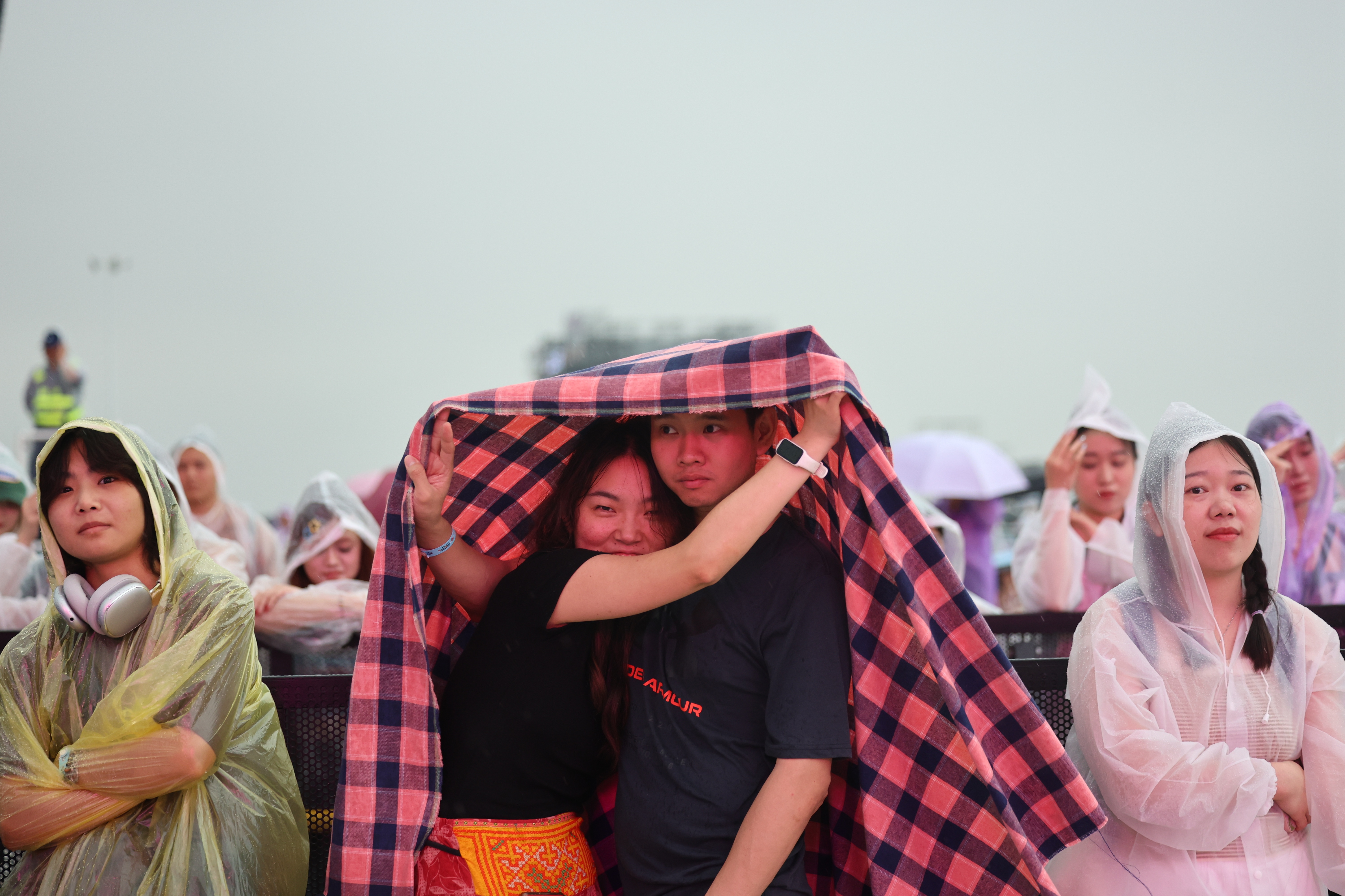 雨中，两名乐迷偎依在一起，享受音乐带来的快乐。