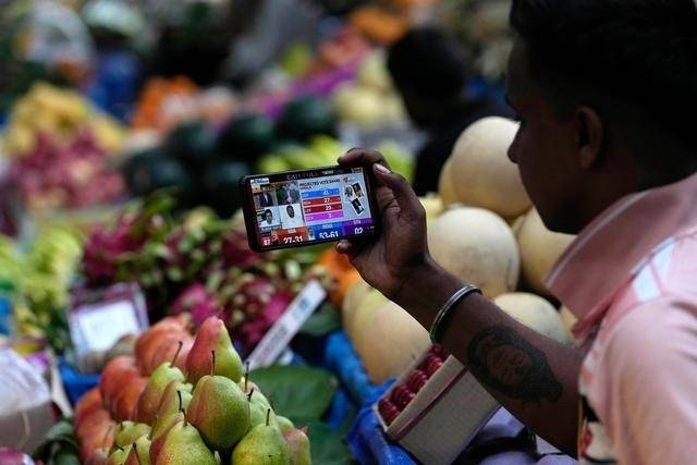 △6月1日，一名商贩在印度孟买用手机观看出口民调结果。
