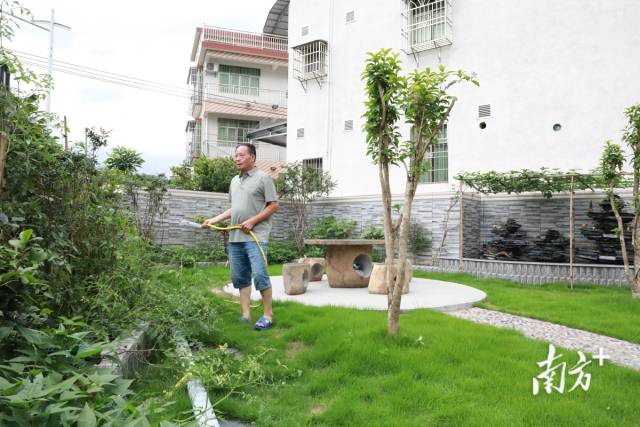 侯北村村民正在自家庭院给花浇水。刘文烽 摄