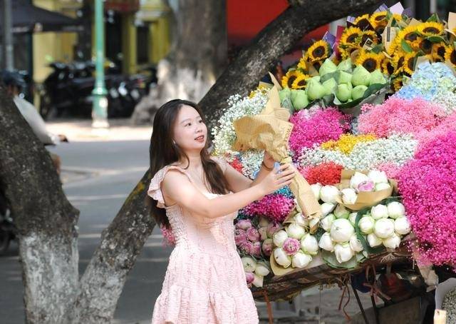 △8月16日，一名越南女子在河内街头一处流动摊前购花。新华社发