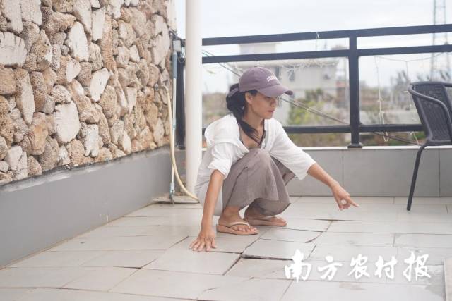 李晓明在民宿露台上检查受损地板，准备重新铺设地砖。
