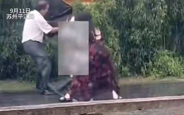 ▲9月11日，江苏苏州平江路一男子持刀伤人，一名穿碎花裙的女生用伞奋力敲打行凶者。图/网络视频截图