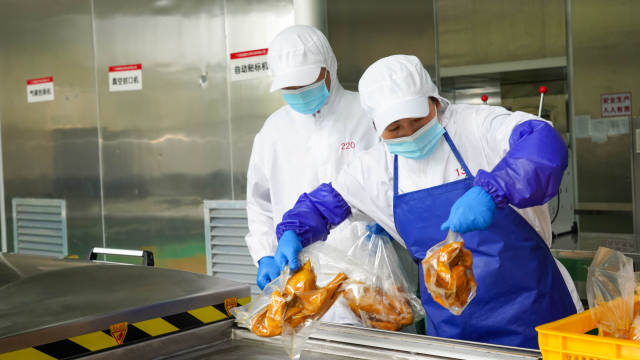 爱健康农牧集团的清远鸡加工车间，工人正在检查产品密封情况。