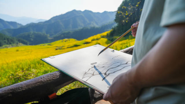 艺术家正在用水墨勾勒出欧家梯田的诗意美景。