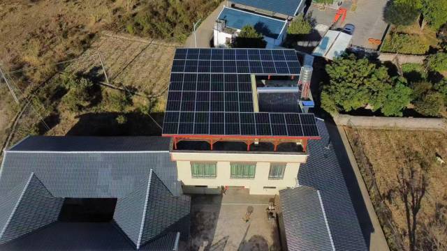 平远县坚持“风貌优先、光伏赋能”，村民在农房屋顶铺上光伏板。