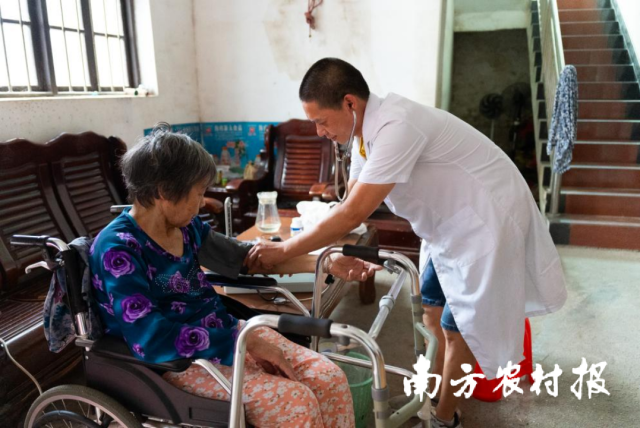 连州镇高堆村委会卫生站医生吴伟标为陈惠杏老人上门送药、测血压。