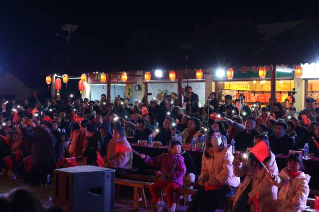 清远市六甲洞村，村民手举手机，为台上的演员应援。