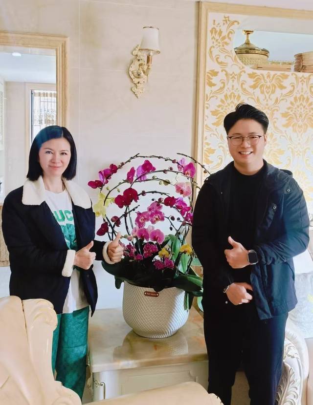 潘天榮（右）將四會蘭花送給唐瑩（左）,。