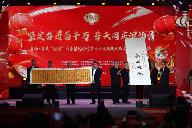 广东省委宣传部副部长、省文明办主任陈晓建、广东省文联党组书记、专职副主席王垂林登台赠予泥沟村“盛世雄风”书法卷轴;广东省委社会工作部副部长王利春、广东省志愿者联合会会长顾作义向村委会赠上书法作品。 广东省委宣传部副部长、省文明办主任陈晓建、广东省文联党组书记、专职副主席王垂林登台赠予泥沟村“盛世雄风”书法卷轴;广东省委社会工作部副部长王利春、广东省志愿者联合会会长顾作义向村委会赠上书法作品。