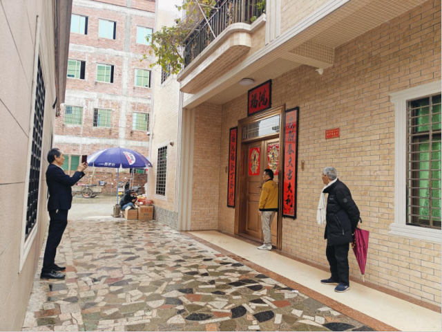 游客在梁文锋家门前与紧闭的大门合影。