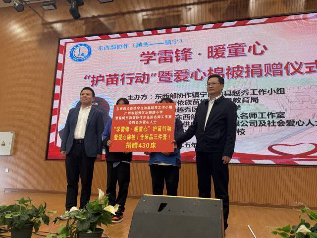 张清波副局长（左）、周龙副局长（右）将爱心棉被移交给学生代表。