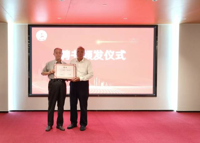 陈开枝（右）为施祖麟（左）颁发“广东省老区建设促进会高级顾问”聘书。