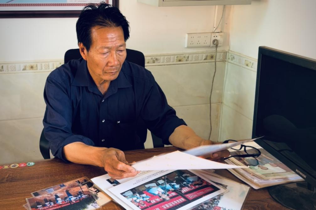 关连强随身携带的一摞照片，记录着十年来的点点滴滴。