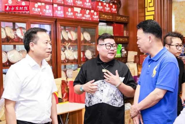 源森鸿鹏茶业负责人彭晓鸿（左二）为调研组介绍经销茶叶品牌。