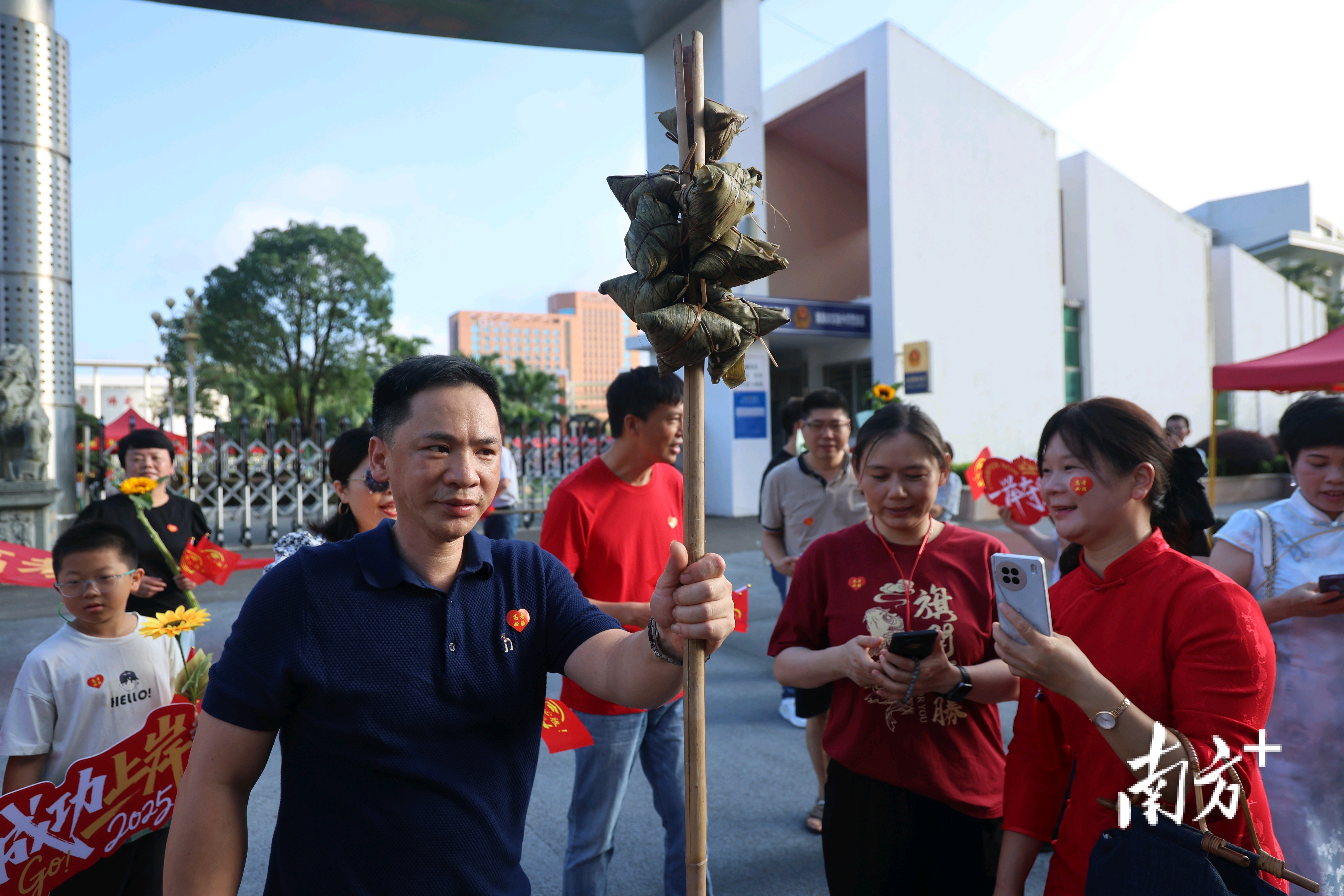 前来为考生鼓劲的家长，手持粽子，寓意“一举高中”。 