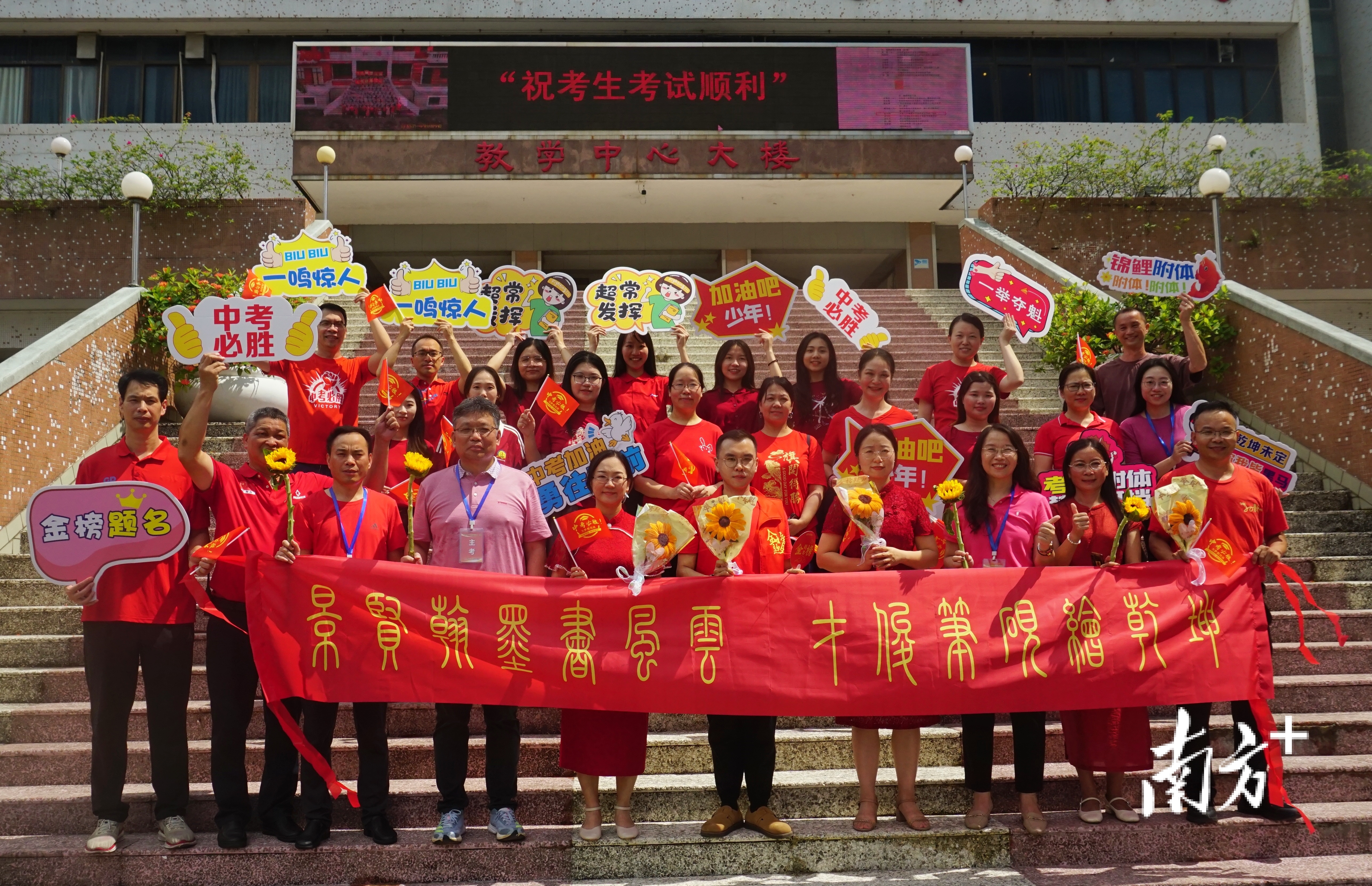 考场外，老师们身穿红衣、高举励志标语牌，隔空为场内考生送祝福。 南方+ 黄烨倩 摄