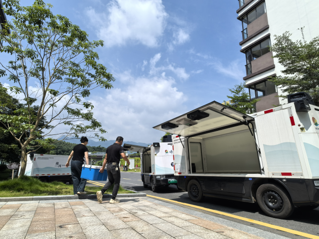 志愿者正在往无人车上搬运配送爱心餐  罗伟科摄