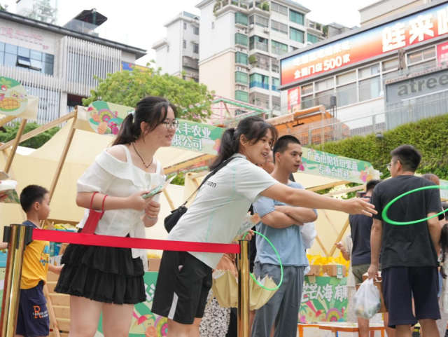 在“壮山农鲜”互动体验区内，市民游客们排起长队，参与趣味挑战赢取芒果礼品。