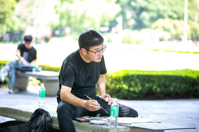 广州美术学院老师黄涛正在古榕树前进行画作。