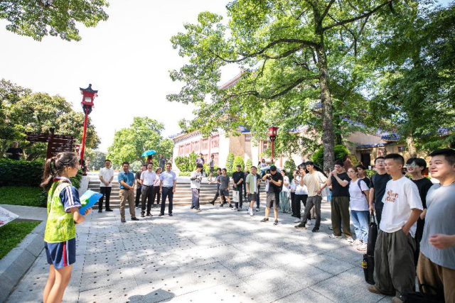 中山纪念堂百年木棉古树下，小小讲解员正在为青年书画艺术家们介绍“木棉王”的历史。