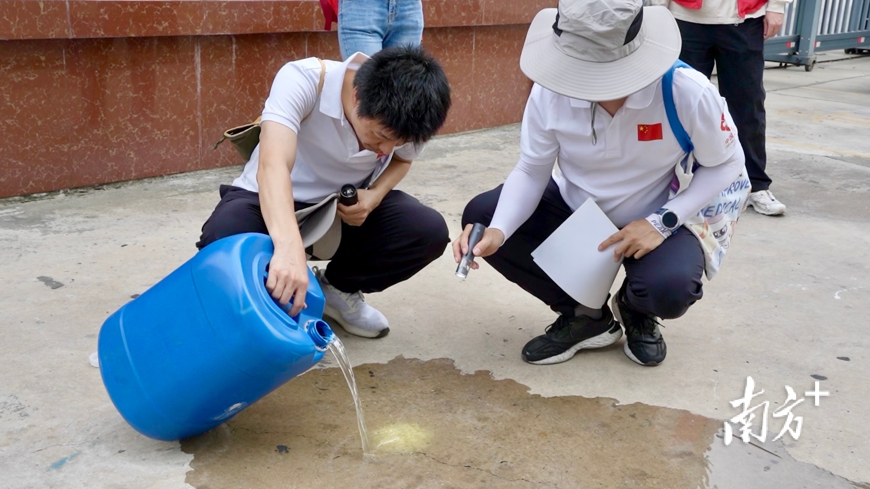 疾控中心工作人员正检查桶中积水有无蚊虫及虫卵。