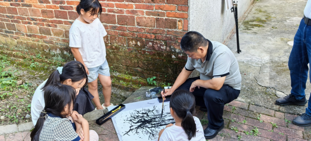 8月9日下午，画家陈伙金在古银杏前写生，引来大元村的小朋友们围观。