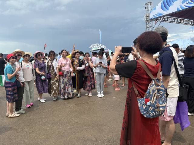 远道而来参加开渔仪式的游客正在码头上合影留念