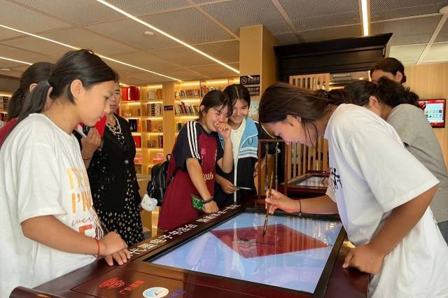 年轻读书者正在体验水代墨电子书法台。