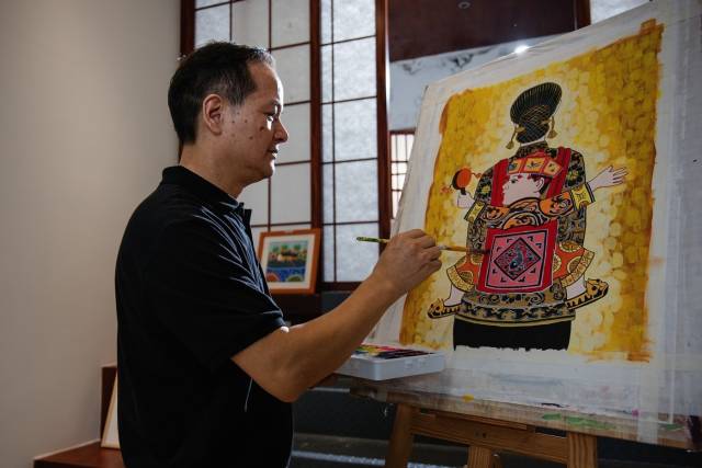 黄伟平正在创作以“母亲”为主题的龙门农民画。（彭华 摄）