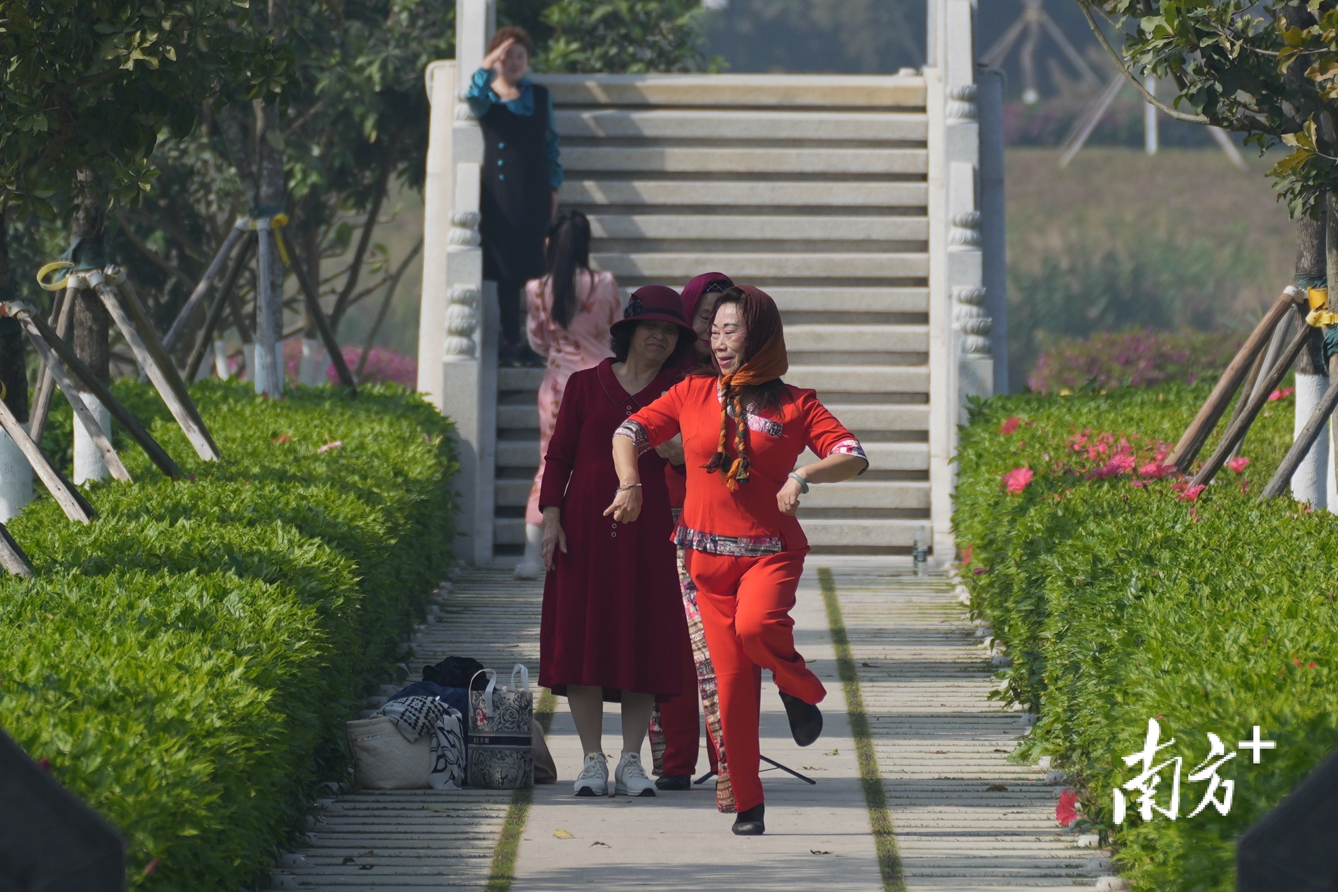 公园里，一身红衣的阿姨随着音乐的节奏翩翩起舞。 