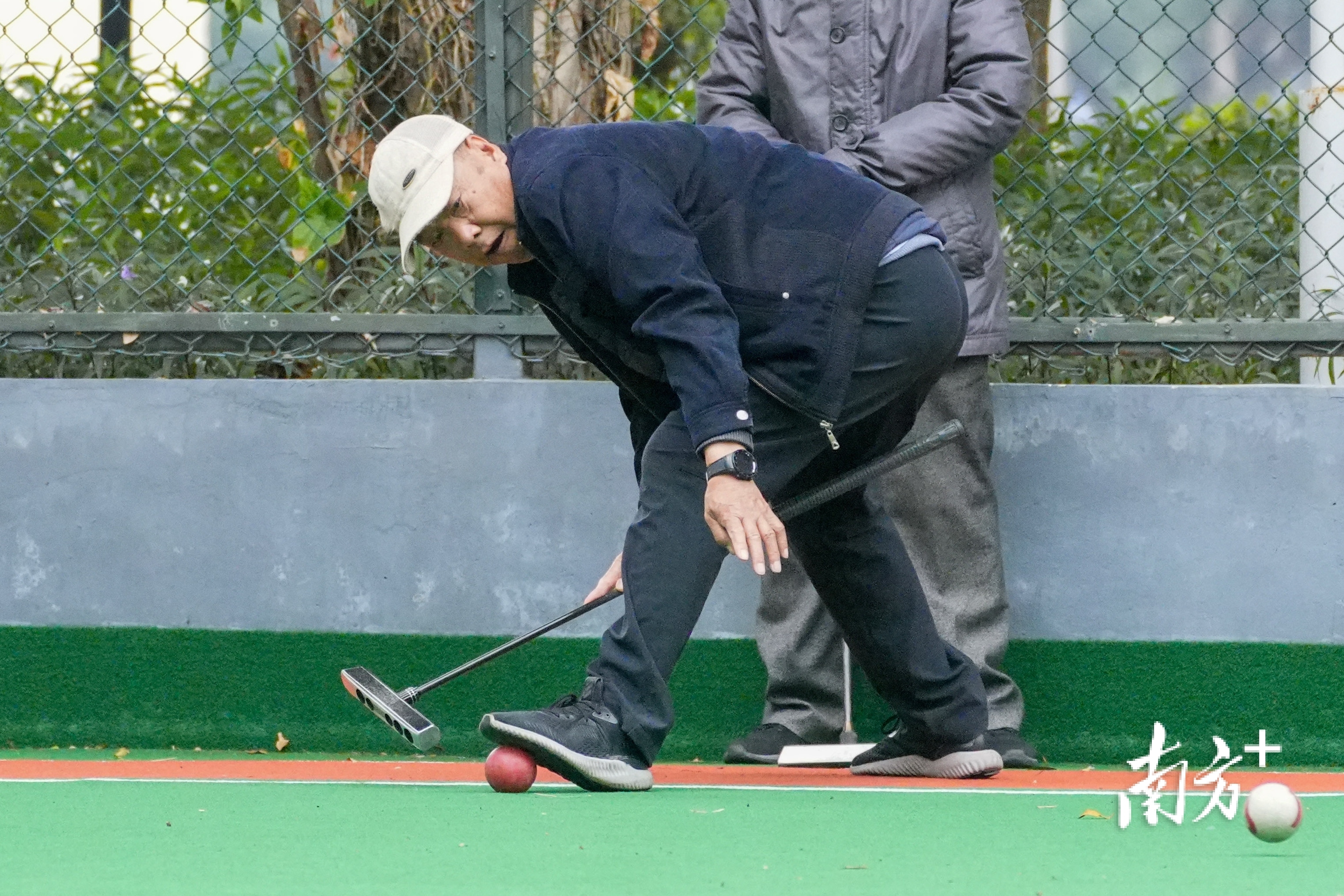 在球场上，老人专注地击球。 