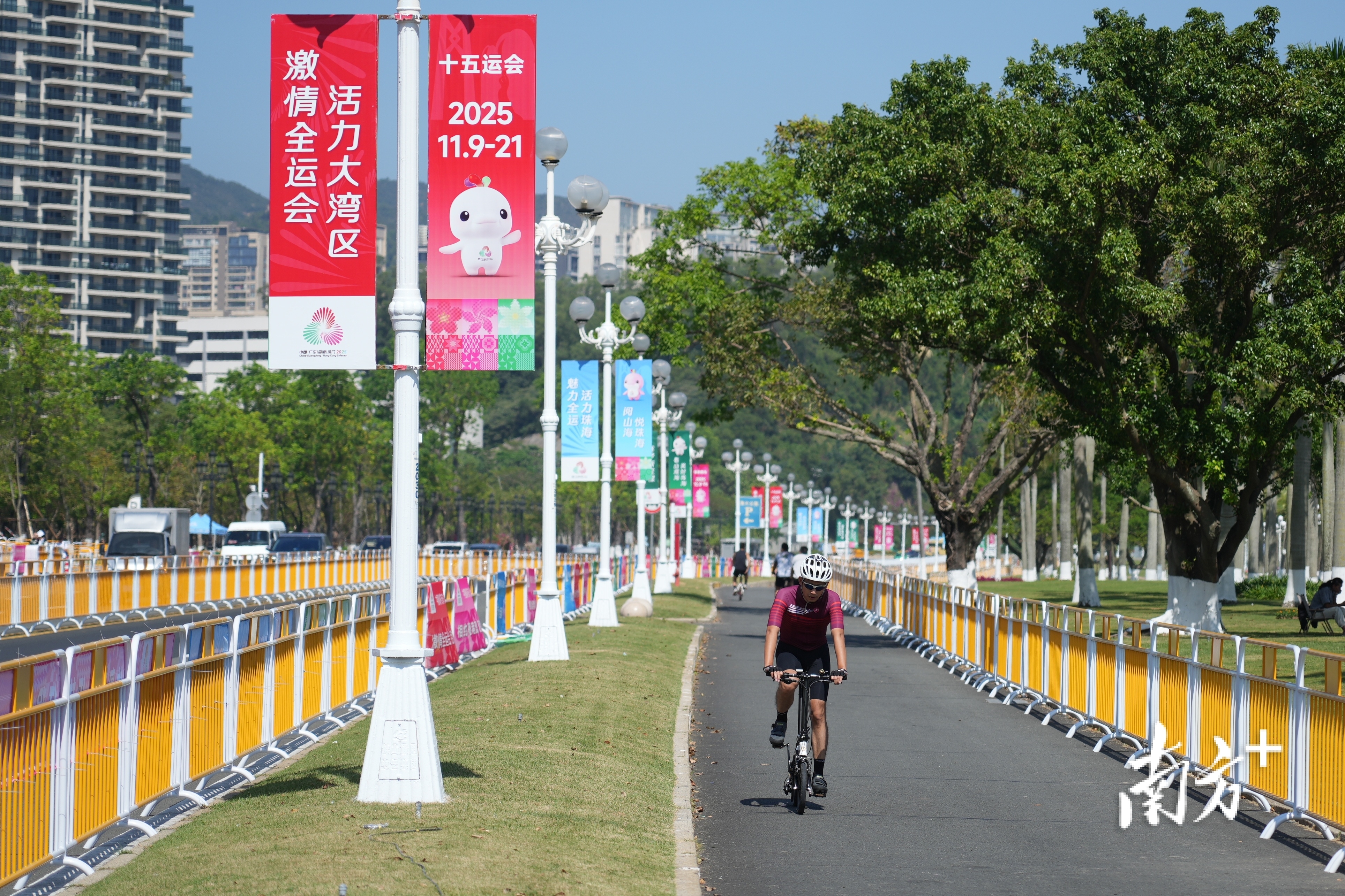 情侣路旁挂满了全运主题海报，骑行爱好者在绿道上骑行。 