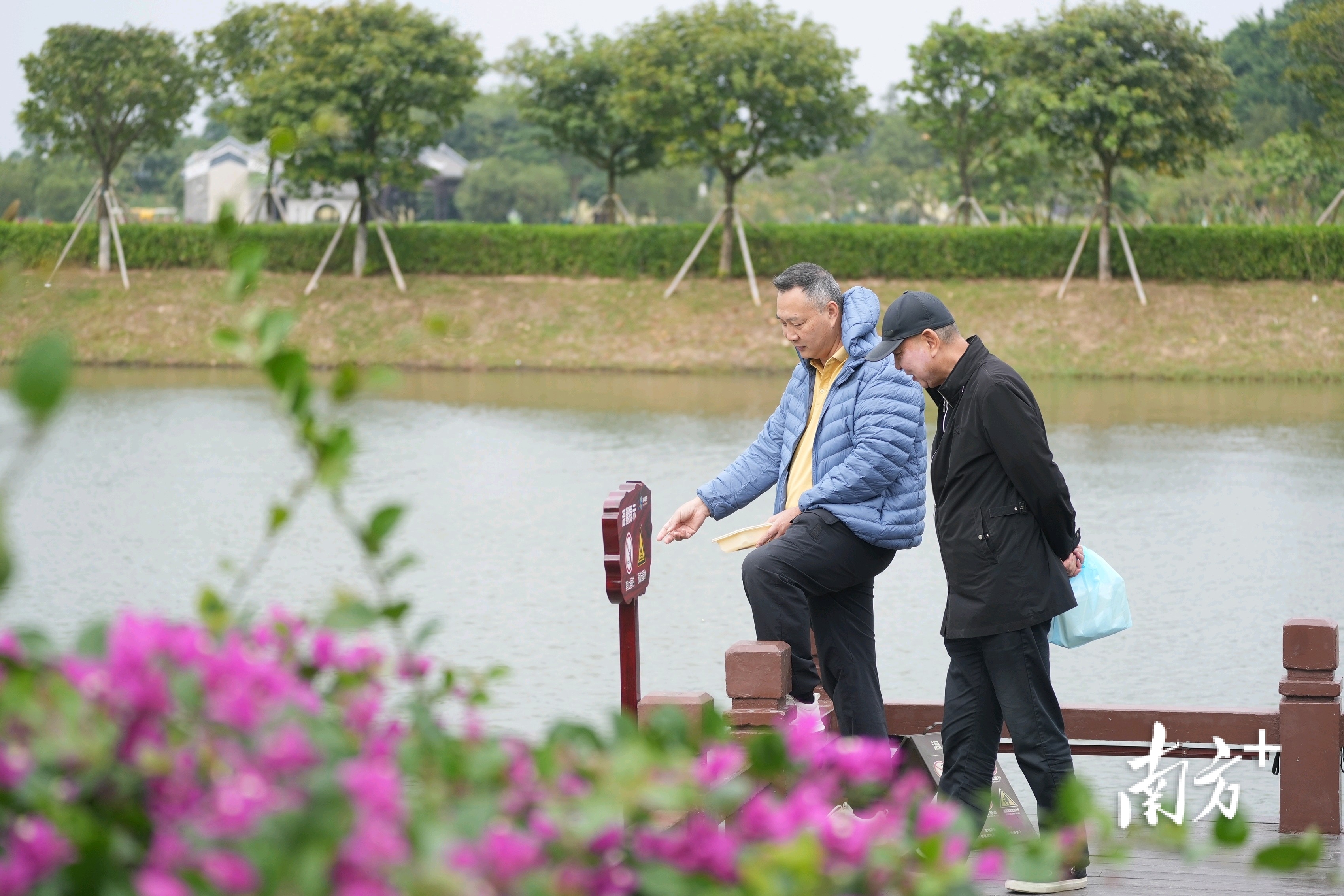 两位大叔在曲桥闲步喂鱼。&nbsp;