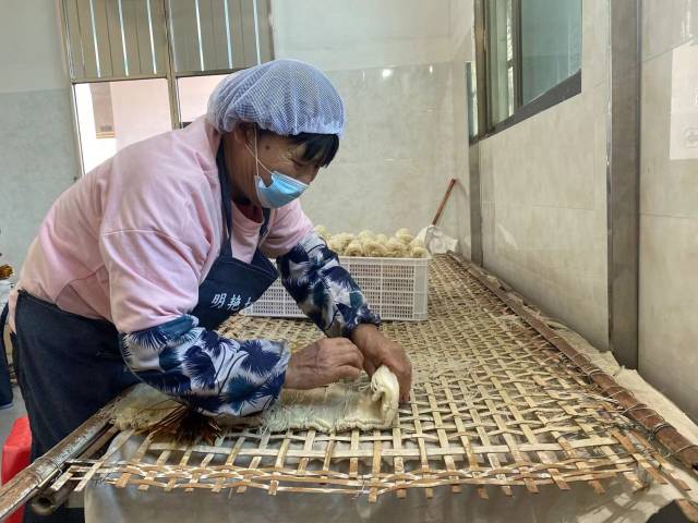 在明艳切粉厂里，工人在包扎晾晒好的岗坪切粉。