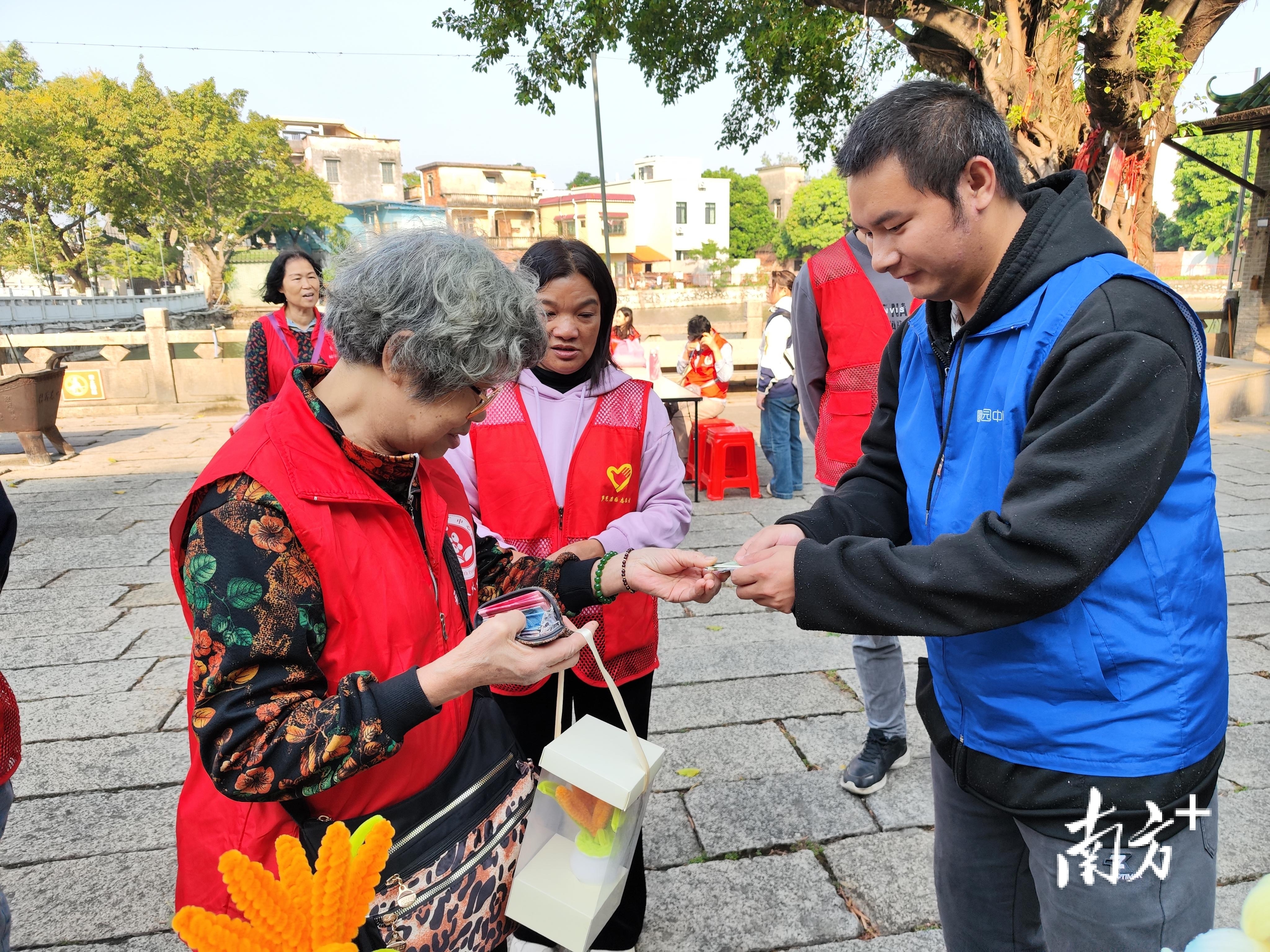 康园中心学员拿着自己做的工艺品,主动推荐给市民。 芦苞镇 供图 康园中心学员拿着自己做的工艺品,主动推荐给市民。 芦苞镇 供图