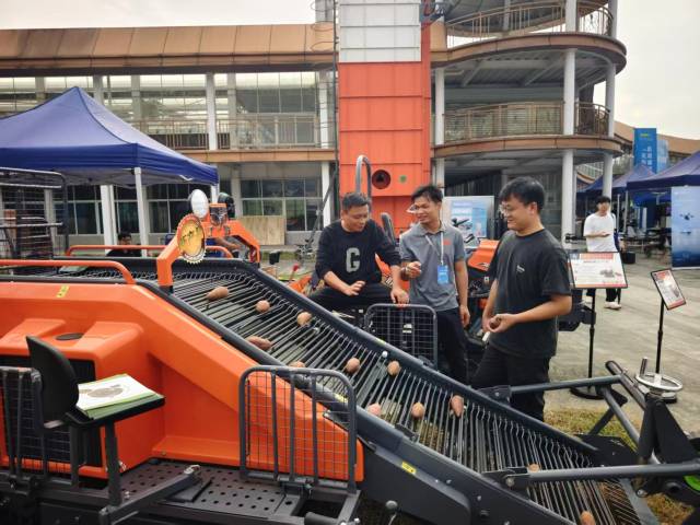 自走式甘薯联合收获机展位前，不少种植大户与农机合作社前来咨询和洽谈。  