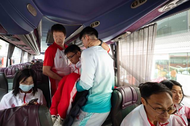 出发前,助教张健忠将行动不便的队员们逐一抱上大巴。