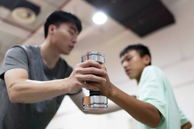 在结束早午两操后,助教林琪深单独留下钟英杰,帮助他用哑铃加练手臂伸展力量。