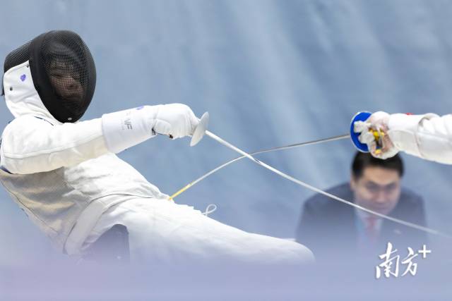 12月12日,在香港赛区男子花剑团体铜牌赛中,广东一团夏永君(左)后仰躲开对手的进攻。