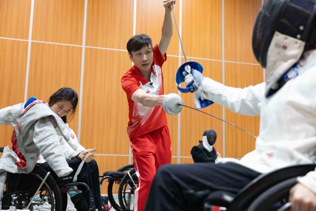 在训练基地中,龙杰正在手把手指导C级运动员出剑的位置。