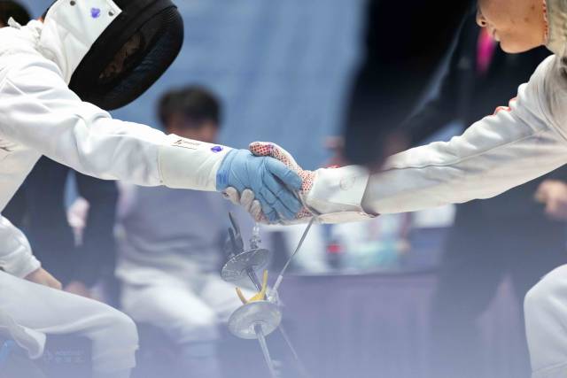 12月12日,在香港赛区男子花剑团体铜牌赛后,广东一团吴安迪(左)与对手握手。