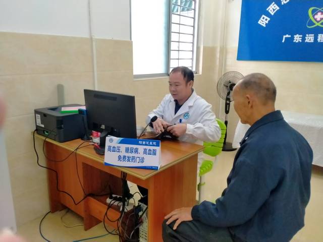 塘口镇下垌村卫生站村医饶桂水为前来取药的村民测量血压