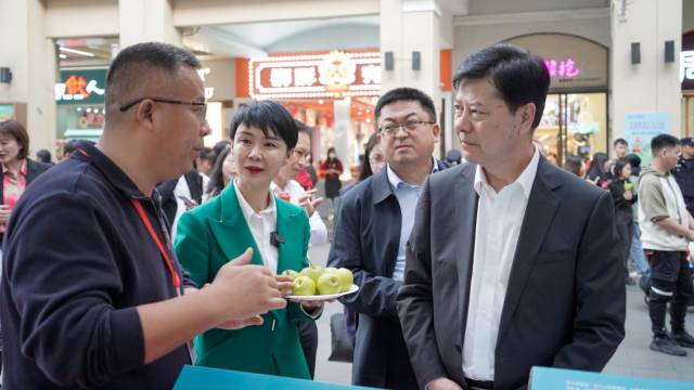 2024年“新春行动促消费”之疆粤冰雪年货节，贺娇龙（左2）在广州北京路为活动嘉宾介绍库尔勒香梨。