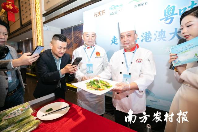 深圳市福田区北海渔村行政总厨刘秋年现场制作连州菜心炒腊味，引得观众纷纷围观拍照。