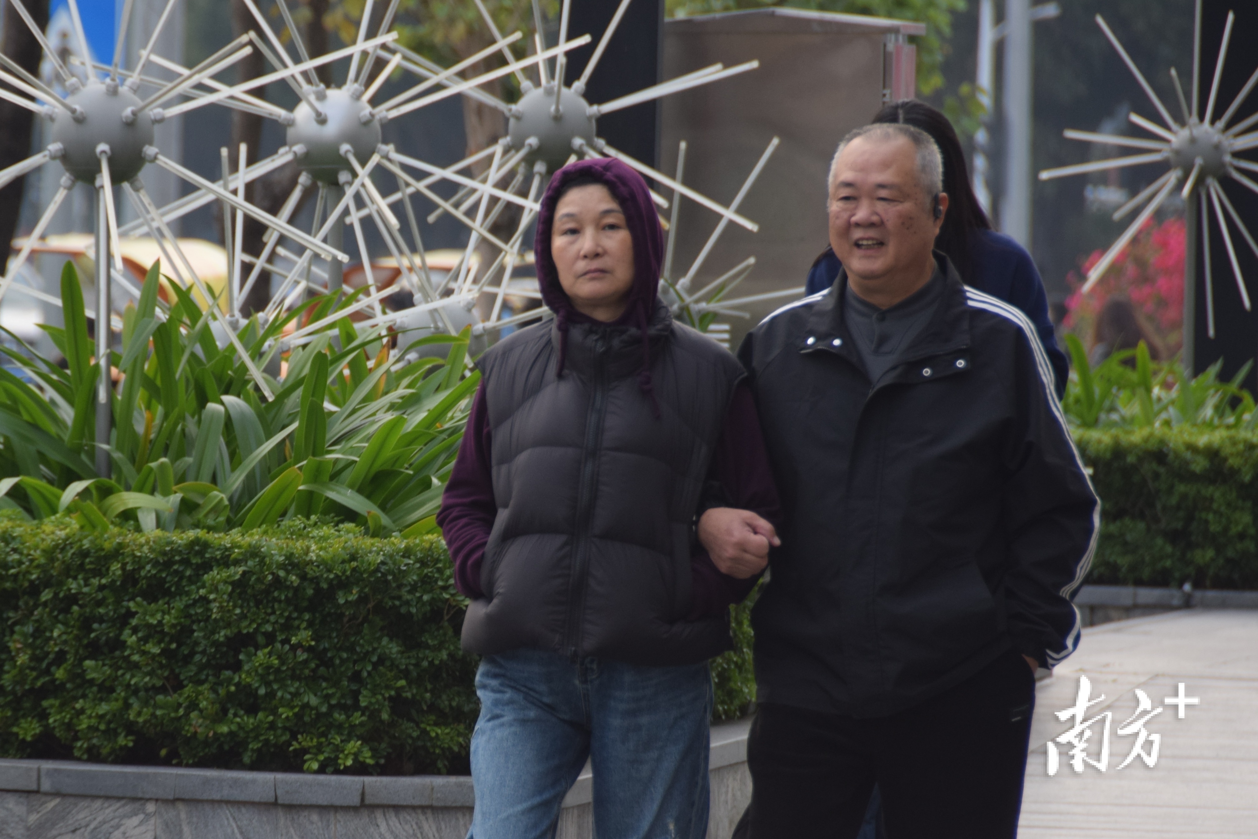 夫妻俩插兜挽手同行。  