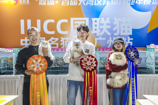 芽芽缅因猫舍负责人覃骏楷（中间）抱着获得第三名的缅因猫。
